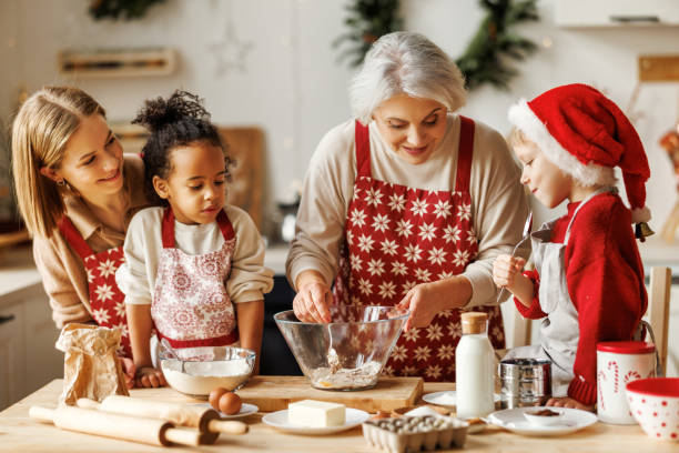 feliz familia multiétnica, abuela, madre e hijos cocinando juntos el día de navidad en la cocina - christmas child cookie table fotografías e imágenes de stock