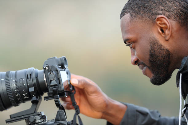 istock Man with black skin checking photos on mirrorless camera 1358004739