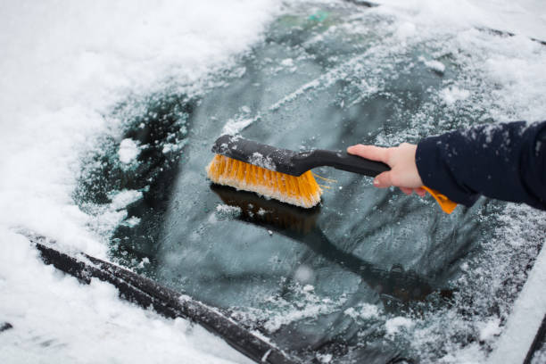 istock Woman removing snow from car windshield 1358006626
