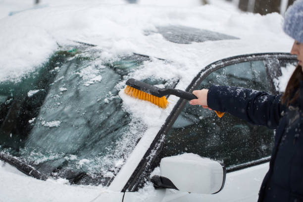 istock Woman removing snow from car windshield 1358006628