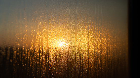 View through a foggy window with drops on it at sunrise