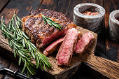 Sliced and Grilled rib eye steak, rib-eye beef marbled meat on a wooden board. Wooden background. top view