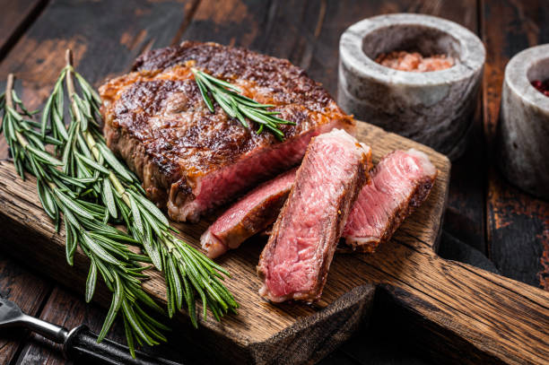 bife de olho de costela fatiado e grelhado, carne de carne de mármore de costela em uma tábua de madeira. fundo de madeira. vista superior - eye fillet - fotografias e filmes do acervo