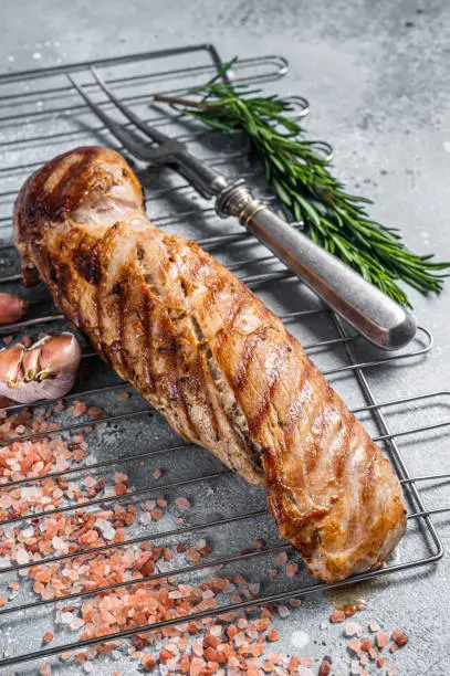 Photo of Grilled pork tenderloin fillet meat on grill. Gray background. Top view