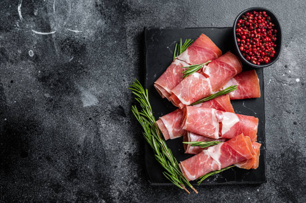 istock Traditional Spanish Jamon Serrano ham on marble board. Black background. Top view. Copy space 1358009498