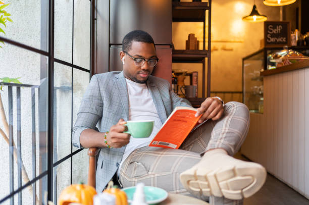 hombre leyendo en la cafetería - hot drink audio fotografías e imágenes de stock