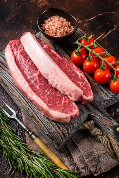 Raw Picanha meat steak, traditional Brazilian beef cut with thyme. Wooden background. Top view.