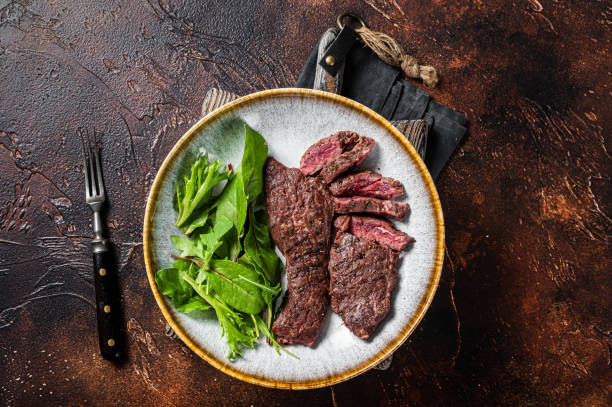 BBQ Grilled flank and Machete skirt steak in plate with vegetable salad. Dark background. Top view. Copy space BBQ Grilled flank and Machete skirt steak in plate with vegetable salad. Dark background. Top view. Copy space. flank steak stock pictures, royalty-free photos & images