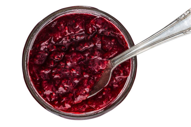 istock Freshly opened jar of raspberry jam with silver spoon isolated on white background 1358011983