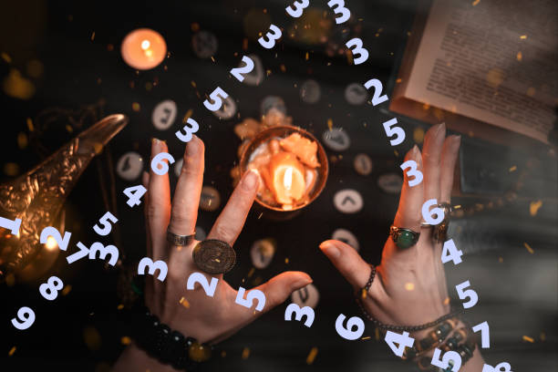 istock Astrology and esotericism. Female witch hands divination over a candle. On a black background lie fortune-telling runes, a book, amulets and a candle. A triangle of numbers in the foreground 1358012879
