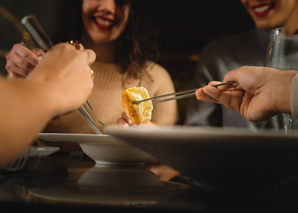 gruppe junger leute essen knödel bei fusion asiatisches essen mit den essstäbchen - nahaufnahme des essens - eating men food chopsticks stock-fotos und bilder