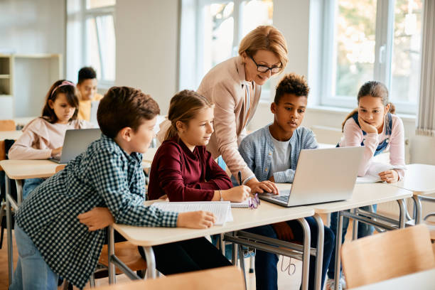 grupo de estudiantes de primaria que tienen clase de computación con su maestro en el aula. - online education fotografías e imágenes de stock