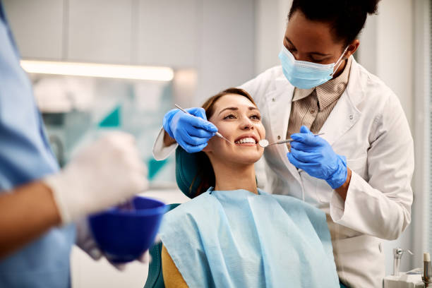giovane donna sorridente che ha un esame dentale nello studio del dentista. - dentist dental hygiene smiling patient foto e immagini stock