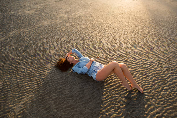 Young girl lying on the sand at sunset
