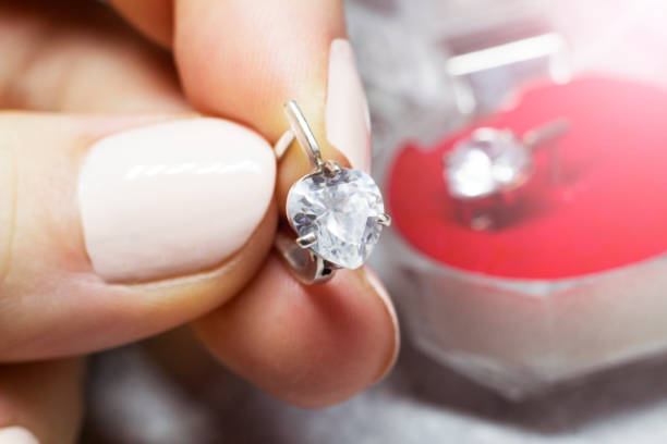 istock A silver earring with a diamond in a woman's hand 1358017026