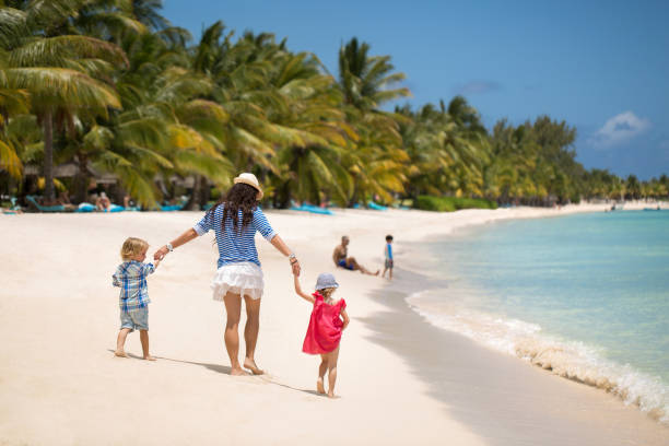 bella madre, figlio e figlia che camminano sulla spiaggia dell'oceano indiano. - sibling baby three people baby girls foto e immagini stock