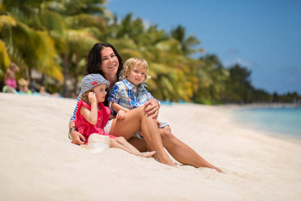 bella madre, figlio e figlia seduti sull'oceano. - sibling baby three people baby girls foto e immagini stock