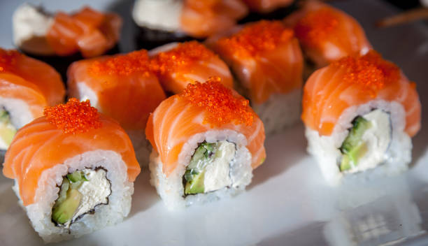 Salmon sushi set. Sushi roll Philadelphia with red fish, salmon, red caviar. Roll with soft avocado and cream cheese under a layer of massago caviar. Classic sushi. Food background stock photo
