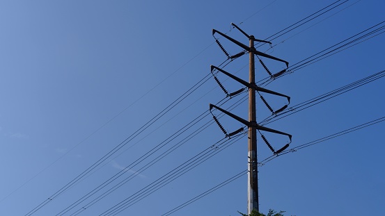 High voltage power cable tower against blue sky background
