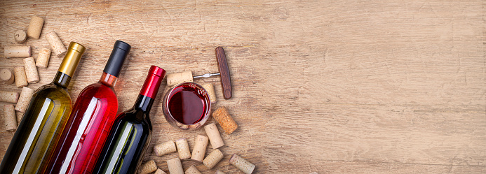 Red and white wine  bottles on wooden background. Top view with copy space