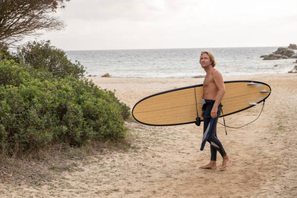 istock Male surfer going to the beach, he carries a surfboard 1358030899