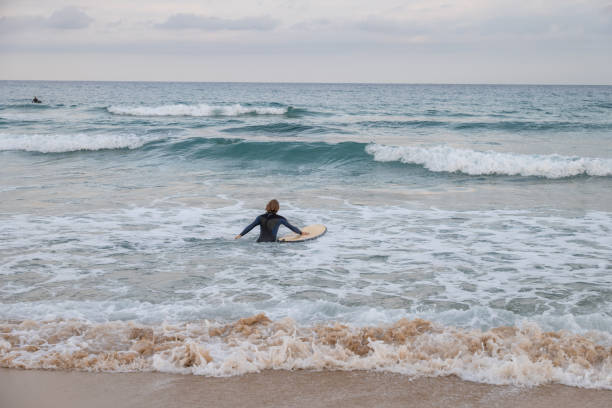 istock Male surfer walks into the water, ready for a session 1358031816