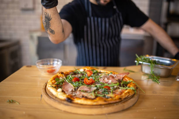 istock Unrecognizable male chef, adding the cherry tomato on th pizza 1358031873