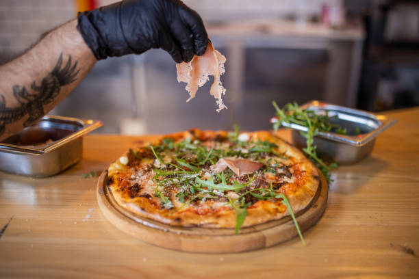 istock For final touch, chef adding the slice of prosciutto on pizza 1358031891