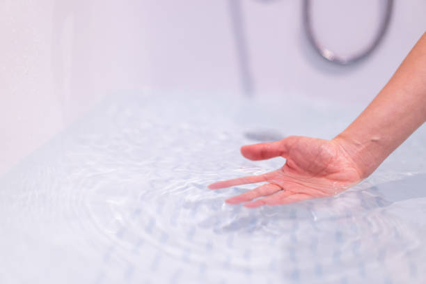 Woman ckecking water temperature in a bath. Beautiful woman touching on the surface of water in bathtub to check the water temperature before get in the bath. Wellness and hydro therapy concept. woman hot shower stock pictures, royalty-free photos & images