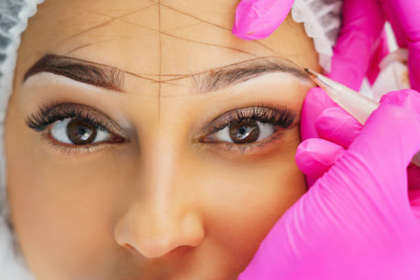 Permanent makeup, tattooing of eyebrows. Cosmetologist applying make up stock photo