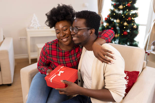 istock Afro man giving Christmas present to girlfriend. 1358034500