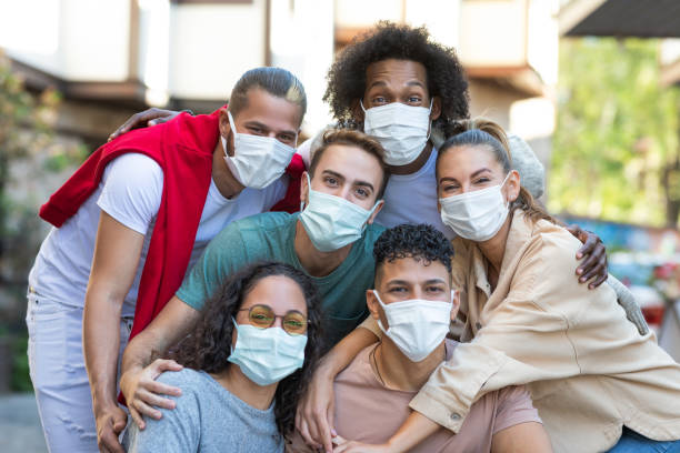 istock Young people hugging and talking together wearing protective face mask 1358035279