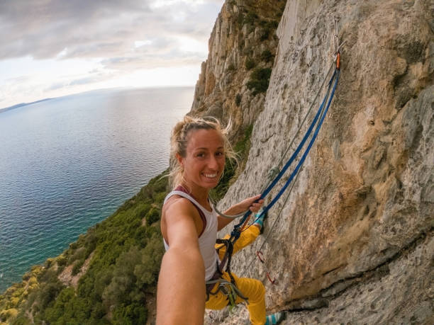 istock Mountain climber on rock face takes a selfie, sea view 1358036094