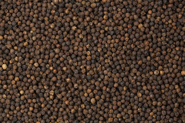 istock Black pepper corns on black background 1358037674