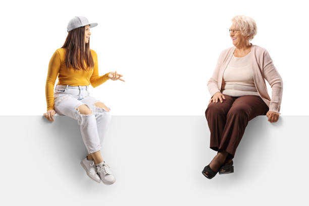 istock Young female with her grandmother sitting on a blank panel and having a conversation 1358037924