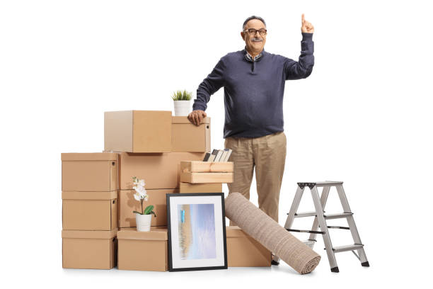 istock Mature man with a pile of cardboard boxes packed for removal pointing up 1358040933