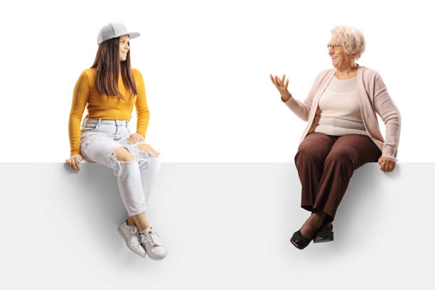 istock Young and elderly female sitting on a blank panel and having a conversation 1358041213