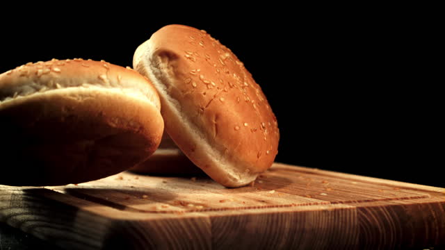Burger buns fall on the cutting board. Filmed is slow motion 1000 frames per second.