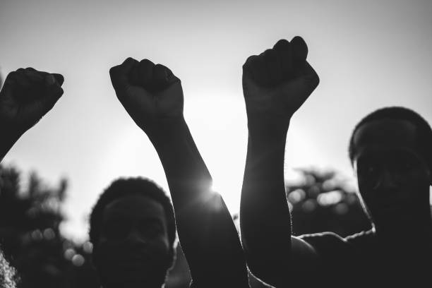 Black demonstrator people holding hands against racism - Focus on civil fists - Black and white edit stock photo