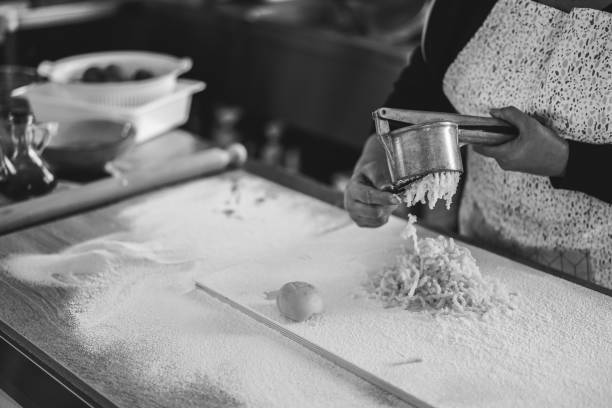 新鮮な手のためにポテトプレスを使用して女性はパスタ工場内のニョッキを作りました - italian cuisine 写真 ストックフォトと画像