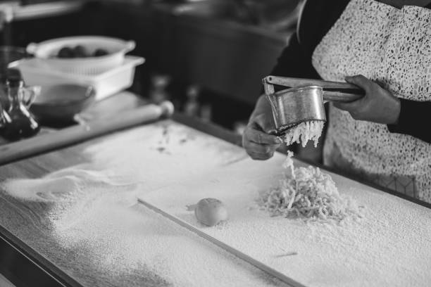 Woman using potato press for fresh hand made gnocchi inside pasta factory