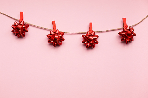 Red bows on a string on a pink background. Christmas concept