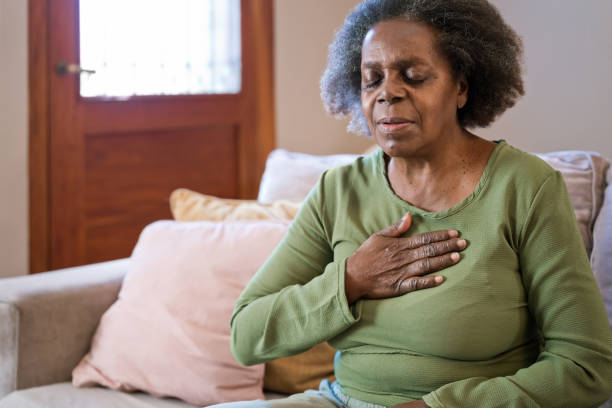 elderly woman having chest pain in living room - chest pain imagens e fotografias de stock