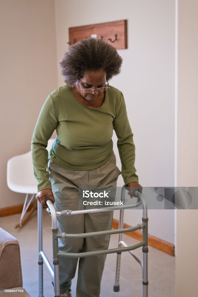 Elderly woman walking with mobility walker Senior woman with mobility walker. Elderly female is walking at home. She is in living room. Mobility Walker Stock Photo