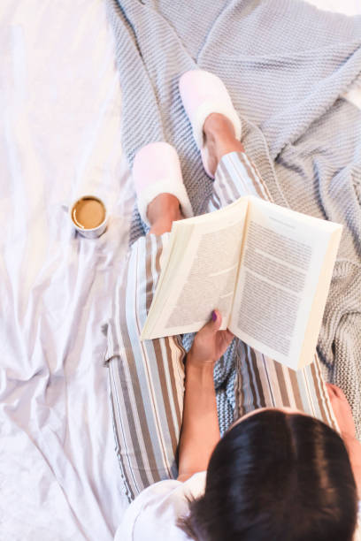istock Girl reading book and drinking coffee in bed 1358047757