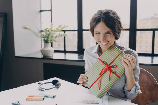 istock Cheerful lady office employee looking at screen broadly smiling showing to computer camera Xmas gift 1358047818