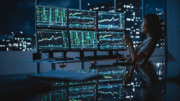 istock Financial Analyst Working on a Computer with Multi-Monitor Workstation with Real-Time Stocks, Commodities and Exchange Market Charts. Businesswoman Comes to Work in Investment Bank Office at Night. 1358049208