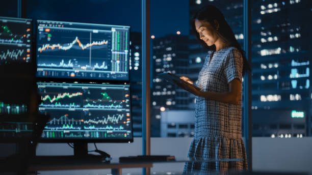 Financial Analyst Talking to Investment Banker in Late Evening at Work. Chatting About Real-Time Stock Chart Data on Tablet Computer. Businesspeople Have a Meeting in Broker Agency City Office. analista financiero hablando con banquero de inversión a última hora de la tarde en el trabajo. chatear sobre datos de gráficos de acciones en tiempo real en una tableta. los empresarios tienen una reunión en la oficina de broker agency city.