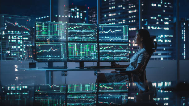 istock Financial Analyst Working on a Computer with Multi-Monitor Workstation with Real-Time Stocks, Commodities and Exchange Market Charts. Businesswoman at Work in Investment Broker Agency Office at Night. 1358049678