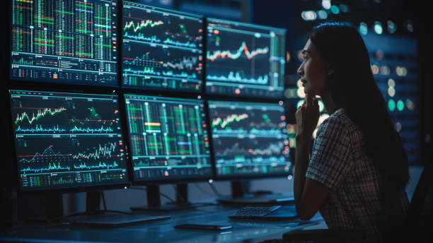 istock Financial Analyst Working on a Computer with Multi-Monitor Workstation with Real-Time Stocks, Commodities and Exchange Market Charts. Businesswoman at Work in Investment Broker Agency Office at Night. 1358049801